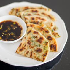 flatbreads on a plate with dipping sauce in a small white bowl next to it