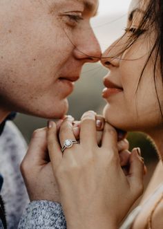 a man and woman kissing each other with rings on their fingers in front of them