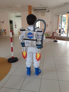 a young boy dressed up as an astronaut standing in front of a white tiled floor