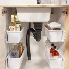 a kitchen sink under a faucet filled with bottles and other household cleaning supplies