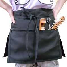 a person wearing an apron holding a pair of scissors and combs in their pockets