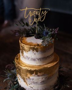 a three tiered cake sitting on top of a wooden table next to a person