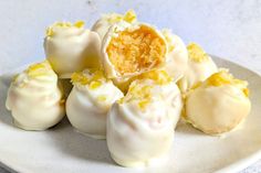 a white plate topped with yellow and white desserts on top of a marble table