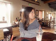 a woman sitting at a table with a drink in her hand