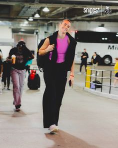 a woman is walking through an airport with her hand on her hip and smiling at the camera