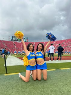 two cheerleaders sitting on the sidelines in front of an empty football stadium