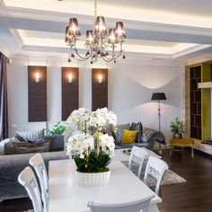 a living room filled with furniture and a chandelier above a white dining table