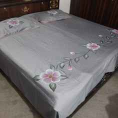 a bed with flowers on it in a room next to a dresser and mirror,