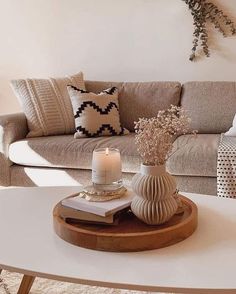 a living room with a couch, coffee table and vase filled with flowers on it