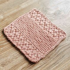 a pink crocheted dishcloth sitting on top of a wooden table