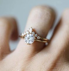 a woman's hand with a diamond ring on top of her finger and an engagement band