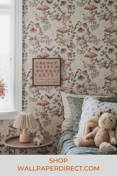 a teddy bear sitting on top of a bed next to a table with a lamp