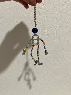 a hand holding a multicolored beaded keychain hanging from a chain