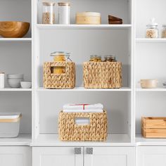 white shelves with wicker baskets and food items on them in a kitchen area that is well organized