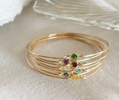 This dainty cubic zirconia birthstone bangle is perfect for brides, bridesmaids, moms, grandmas, or yourself. A dainty CZ Diamond lends glamour and sparkle to create a look that is perfect for stacking, layering, and makes the perfect gift or bangle bracelet for everyday wear. - Available in 14k gold-filled or bronze both are wonderful options  - CZ diamond cubic zirconia in your choice: A. Emerald Green B. Sapphire Blue C. Garnet Red D. Topaz Yellow E. Aqua Blue F. Amethyst Purple or G . Clear Birthstone Charm Necklace, Topaz Yellow, Bronze Bracelets, Gifts For Grandma, Garnet Red, Blue C, Birthstone Bracelets, Amethyst Purple, Cz Diamond