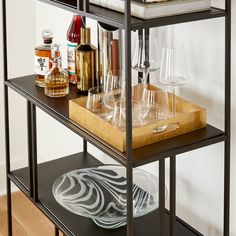 a shelf filled with glasses and bottles on top of a wooden table