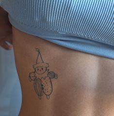 a small tattoo on the side of a woman's lower back, with a teddy bear wearing a party hat