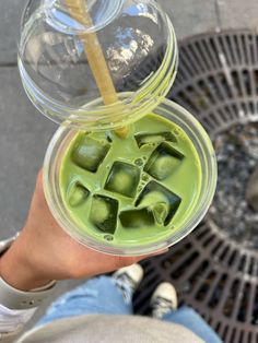 a person holding a cup with ice cubes in it and a straw sticking out of the top