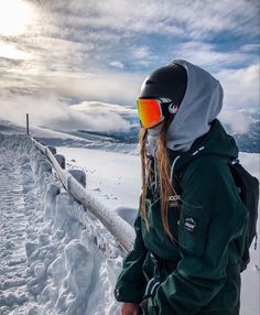 a person standing on top of a snow covered slope wearing skis and goggles