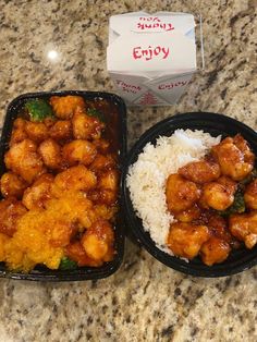 two black plastic containers filled with food on top of a marble counter topped with rice and broccoli