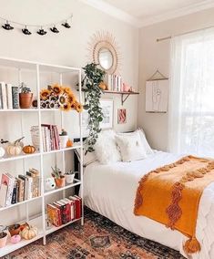 a white bed sitting in a bedroom next to a window filled with lots of books