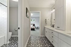 a white bathroom with black and white tile flooring