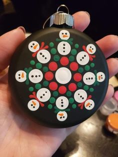 a hand holding a christmas ornament with snowmen on it