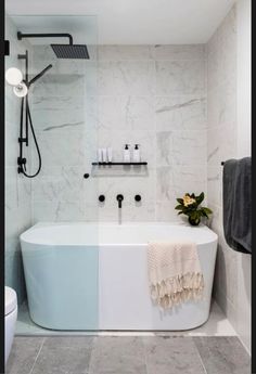 a white and blue bathtub in a bathroom next to a toilet with a black faucet