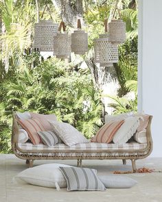 a couch sitting on top of a white floor next to pillows and lamps hanging from the ceiling