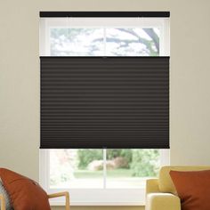 a living room with two couches and a window covered in brown cellular shade blinds