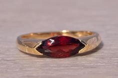 This stunning piece, known as The Crimson Marquise Ring, features a captivating marquise-cut garnet at its center set east to west. The rich, deep red garnet is elegantly set in a 14 karat yellow gold band, designed with sleek, modern lines that add a touch of sophistication. The ring is currently a finger size 7 but can be adjusted to any finger size for an additional charge upon request, ensuring a perfect fit. Love this piece, but don't have the money to spend right now? We offer FREE layaway on every item in our shop. With just 20% down, take one full year (interest-free) to pay off your new jewelry! There are no hidden fees or charges, ever. For more information on our layaway policy, please contact us. Each piece has been hand-selected and meticulously identified and graded by a Grad Grad Rings, Garnet Wedding Rings, Garnet Wedding, Cut Orange, Garnet Engagement Ring, Red Rings, Marquise Ring, Garnet Ring, Garnet Rings