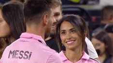 two soccer players in pink uniforms standing next to each other with fans watching from the stands