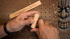 a man is working on an object with wood carving tools in front of a wooden mask