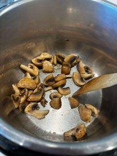 mushrooms being cooked in a pot with a wooden spoon