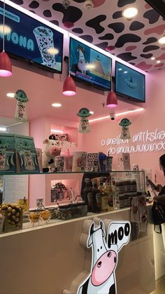 a woman standing in front of a counter with food on it and two televisions hanging from the ceiling