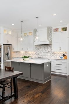 a large kitchen with white cabinets and wood flooring, along with an island in the middle