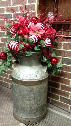 a large metal container filled with red and green ornaments next to a brick wall covered in greenery