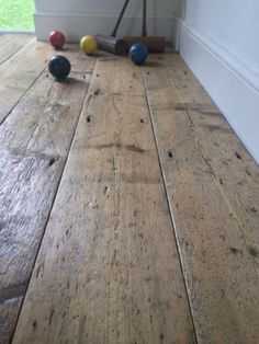 an old wooden floor with balls on it and a broom leaning against the wall next to it