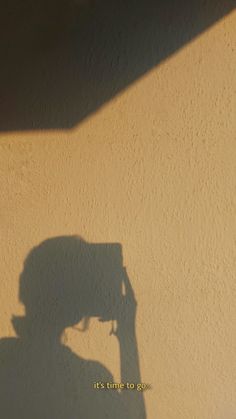 the shadow of a person's head on a wall with a camera attached to it