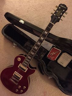 an electric guitar is laying on the floor next to its case, which also holds it's accessories