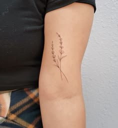 a woman's arm with a small flower tattoo on the left side of her right arm