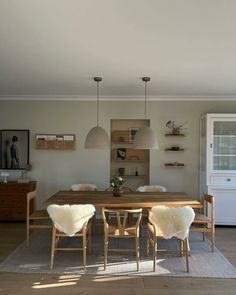 a dining room table and chairs with sheepskin rugs on the floor in front of it