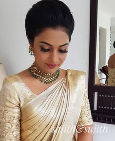 a woman wearing a gold sari and green necklace