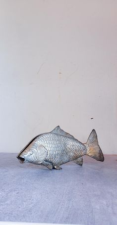 a fish figurine sitting on top of a table next to a white wall