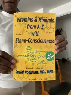 a person holding up a book about vitamins and minerals from a to z with ethno - consciousness