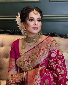 a woman in a red and gold sari sitting on a couch