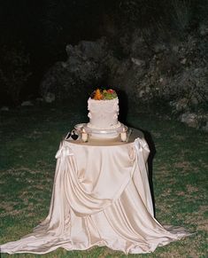 a wedding cake sitting on top of a table covered in white cloths and candles