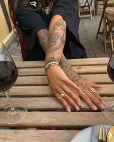 a woman sitting at a wooden table with two wine glasses on it and her hand resting on the table