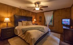 a bedroom with wood paneled walls and ceiling fan