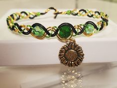 A colored copper wire woven bracelet with three glass beads and a metal sunflower charm attatched. The wire is yellow, black and peridot colored. The color of the charm can be gold or silver colored. Metal Sunflower, Sunflower Charm, Peridot Color, Woven Bracelet, Wire Weaving, Woven Bracelets, The Wire, Yellow Black, Copper Wire